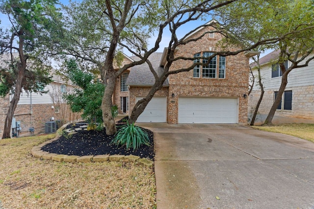 traditional-style house with a garage, brick siding, driveway, and central air condition unit