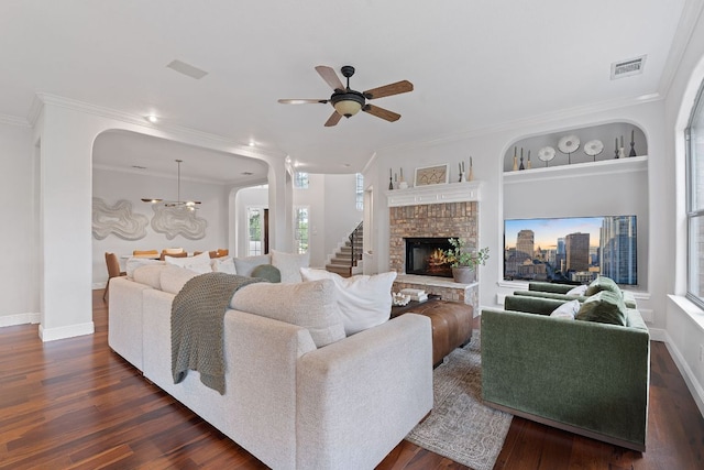 living area with ceiling fan with notable chandelier, visible vents, baseboards, ornamental molding, and dark wood finished floors