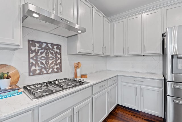 kitchen featuring stainless steel appliances, decorative backsplash, white cabinetry, light stone countertops, and under cabinet range hood