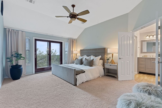 bedroom featuring lofted ceiling, access to outside, light carpet, and ensuite bath