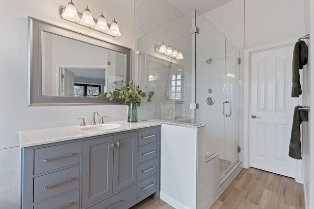 bathroom with a healthy amount of sunlight, a shower stall, vanity, and wood finished floors