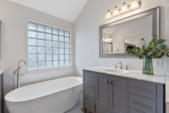 full bath featuring vaulted ceiling, a freestanding tub, and vanity