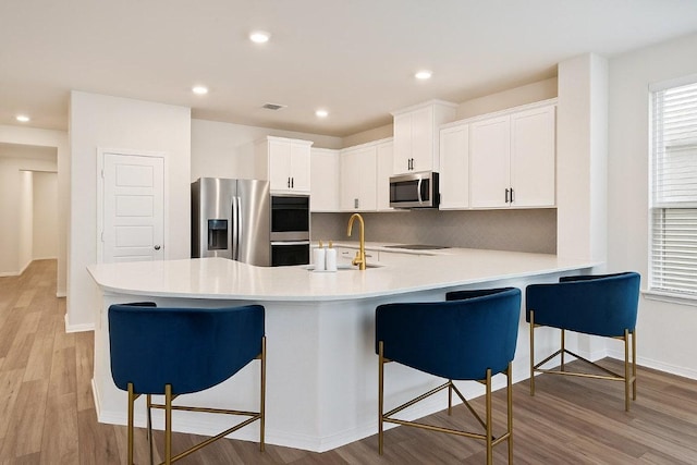 4805 Cressal Dr, Pflugerville, TX 78653 - kitchen with appliances with stainless steel finishes, a sink, light wood finished floors, a peninsula, and a kitchen breakfast bar