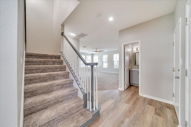 staircase with a ceiling fan, baseboards, and wood finished floors