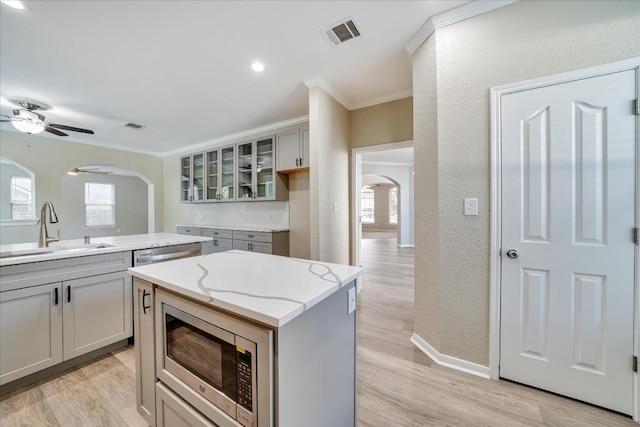 kitchen with arched walkways, visible vents, a sink, and stainless steel microwave