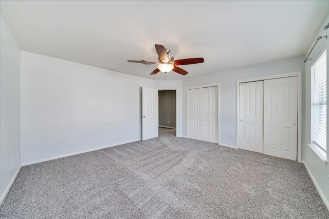 unfurnished bedroom with a ceiling fan, carpet, baseboards, and multiple closets