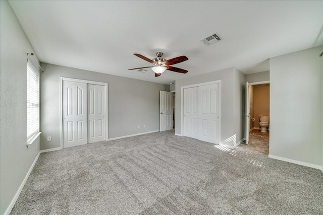 unfurnished bedroom featuring visible vents, baseboards, multiple closets, and carpet flooring