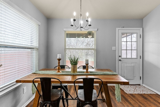 dining area with baseboards, wood finished floors, and an inviting chandelier