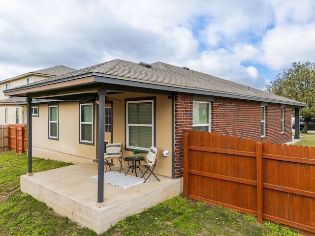 back of house featuring a shingled roof, a patio area, fence, and brick siding