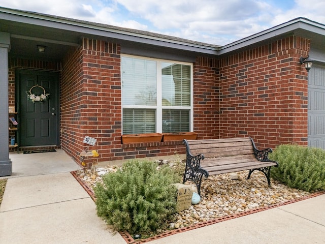 doorway to property with a garage and brick siding