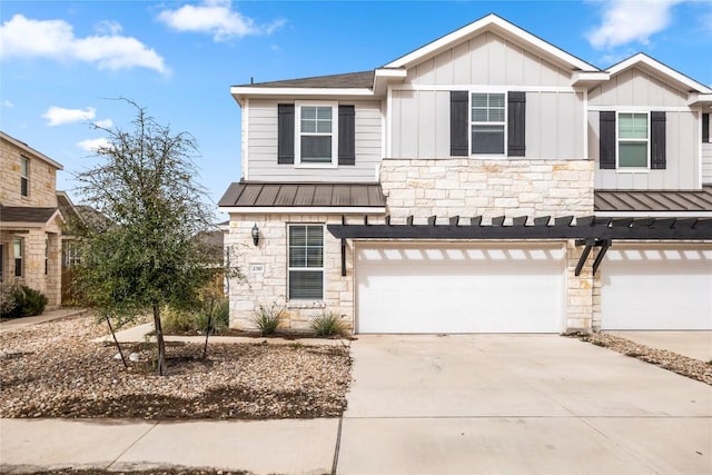 view of front of home featuring concrete driveway, stone siding, metal roof, a standing seam roof, and board and batten siding