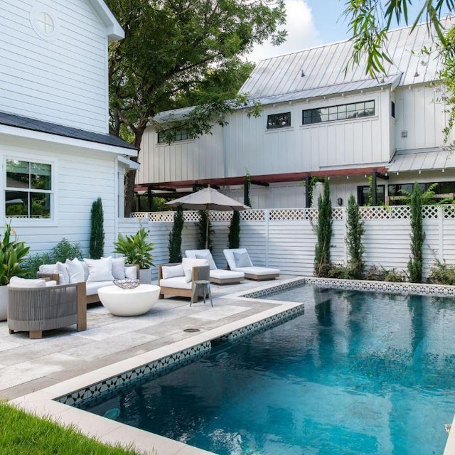 exterior space featuring a fenced in pool, outdoor lounge area, board and batten siding, a patio area, and a fenced backyard