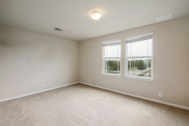 empty room featuring visible vents, light colored carpet, and baseboards