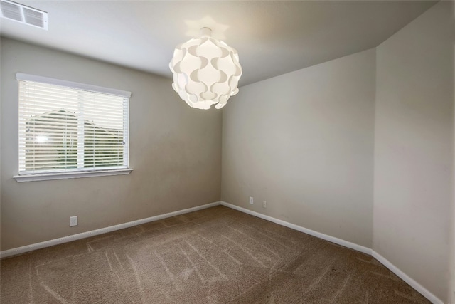 empty room featuring a chandelier, visible vents, baseboards, and carpet floors