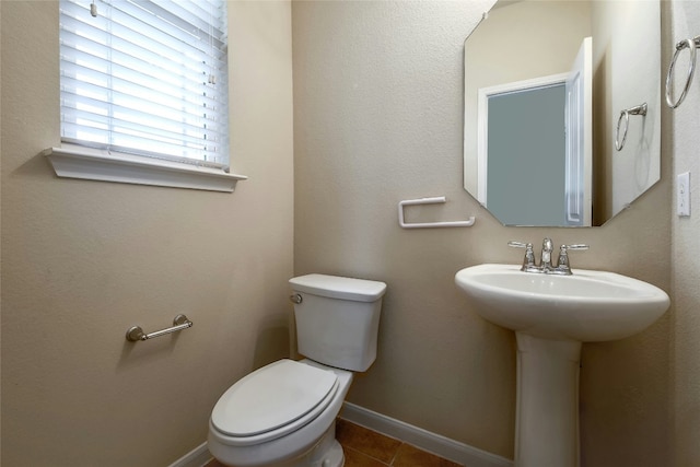 half bath with tile patterned floors, baseboards, and toilet