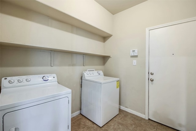 clothes washing area featuring baseboards, light tile patterned flooring, laundry area, and washing machine and clothes dryer