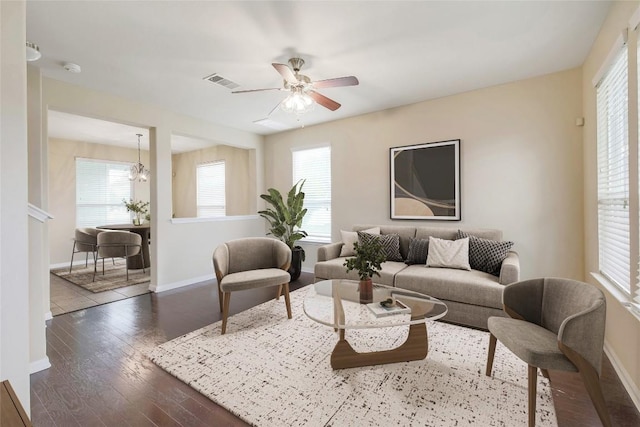 living room with visible vents, baseboards, wood finished floors, and ceiling fan with notable chandelier