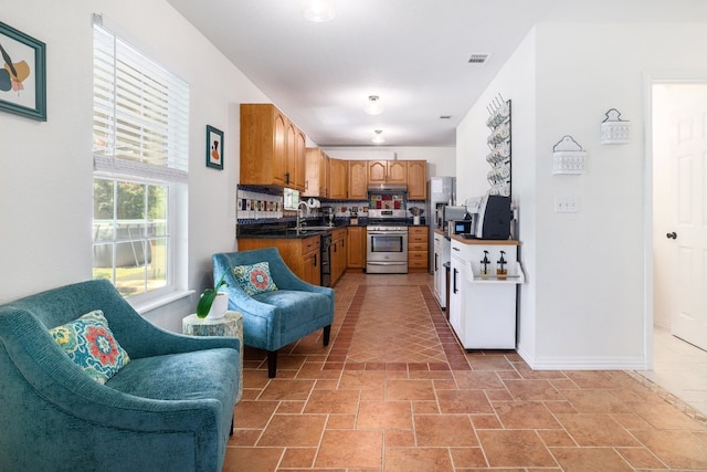 kitchen with visible vents, dark countertops, gas range, open floor plan, and a sink