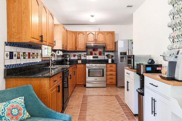 kitchen with tasteful backsplash, visible vents, stainless steel appliances, under cabinet range hood, and a sink