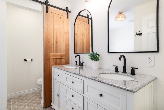 full bath featuring baseboards, a sink, toilet, and double vanity