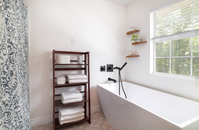 full bath with a soaking tub and baseboards