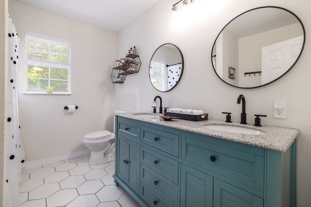 full bathroom with baseboards, a sink, toilet, and double vanity