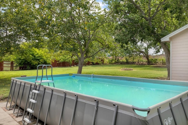 outdoor pool with a fenced backyard and a lawn