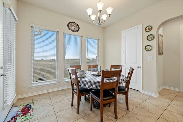 dining room with a chandelier, arched walkways, baseboards, and light tile patterned floors