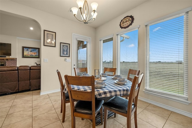 dining room with arched walkways, baseboards, an inviting chandelier, and light tile patterned floors