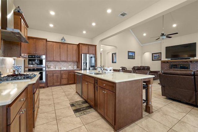 kitchen featuring arched walkways, a sink, visible vents, appliances with stainless steel finishes, and wall chimney exhaust hood