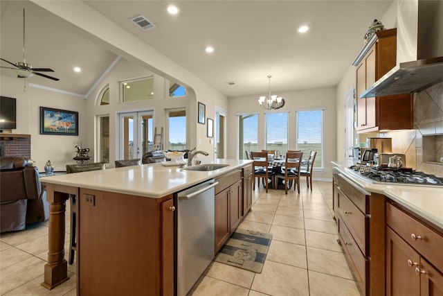 kitchen with stainless steel appliances, visible vents, open floor plan, a sink, and wall chimney exhaust hood