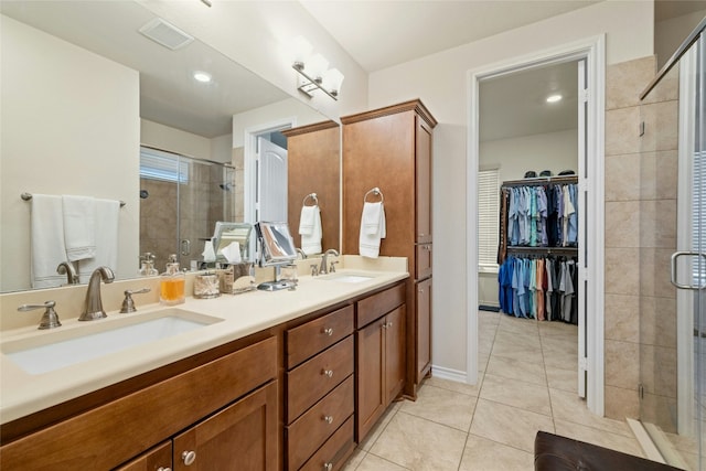 bathroom featuring a stall shower, tile patterned flooring, a walk in closet, and a sink