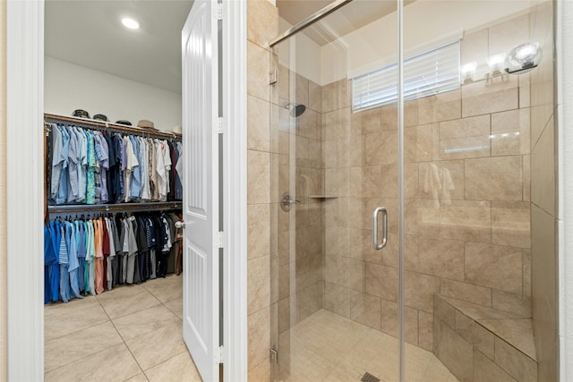 full bathroom with a walk in closet, a shower stall, and tile patterned floors