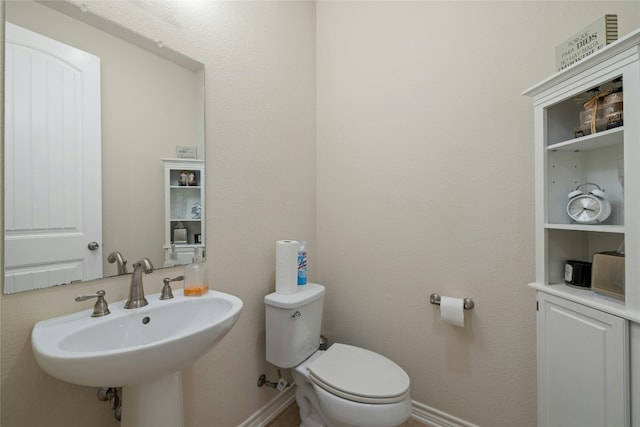 bathroom with a sink, toilet, and baseboards