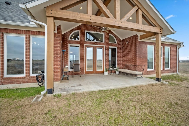 rear view of house featuring brick siding, a ceiling fan, roof with shingles, a lawn, and a patio area