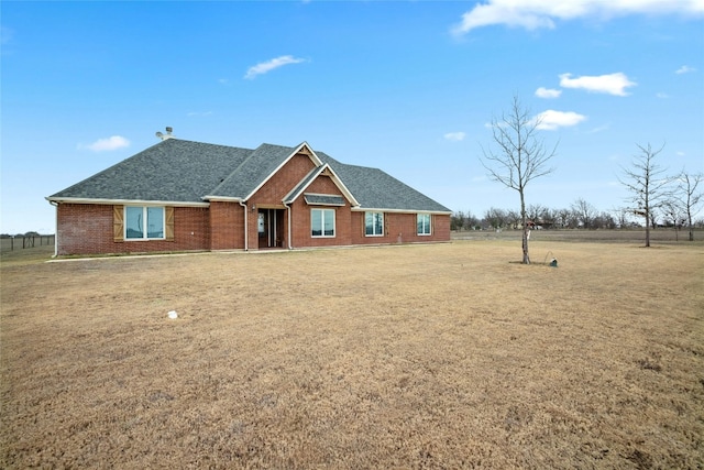 single story home with a shingled roof, brick siding, and a front lawn