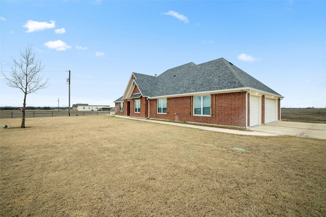 view of home's exterior with brick siding, fence, concrete driveway, roof with shingles, and a lawn