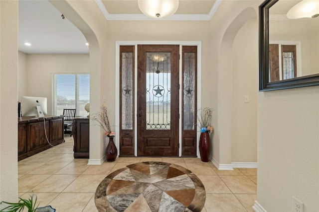 entrance foyer featuring arched walkways, ornamental molding, light tile patterned flooring, and baseboards