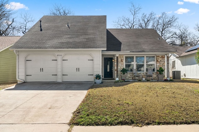 view of front of property featuring roof with shingles, a garage, cooling unit, stone siding, and a front lawn