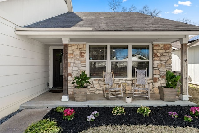 property entrance with stone siding, a shingled roof, and a porch