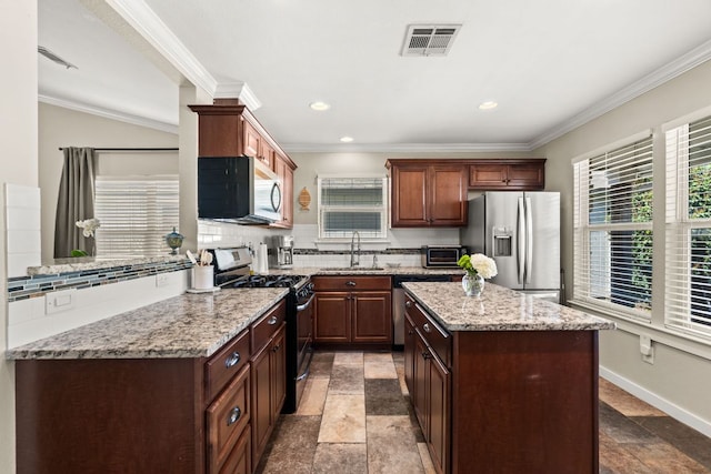 kitchen featuring stainless steel appliances, a sink, visible vents, decorative backsplash, and a center island