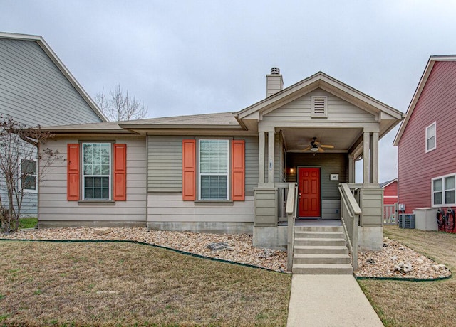 view of front of house with a front yard, ceiling fan, a chimney, and central AC unit