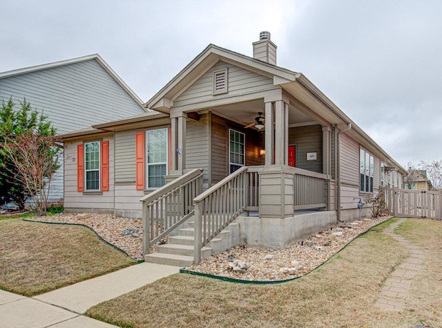 view of front of house featuring a ceiling fan, fence, a chimney, and a porch