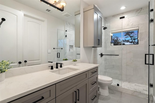 bathroom featuring visible vents, a shower stall, toilet, and vanity