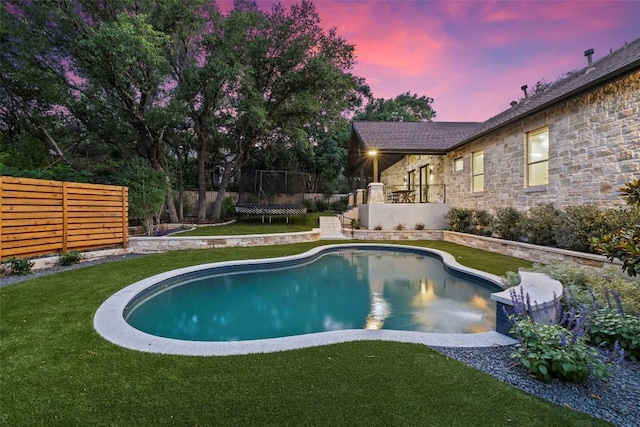 pool with a yard, a trampoline, and fence