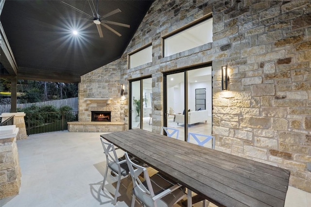 view of patio / terrace with ceiling fan, fence, an outdoor stone fireplace, and outdoor dining area