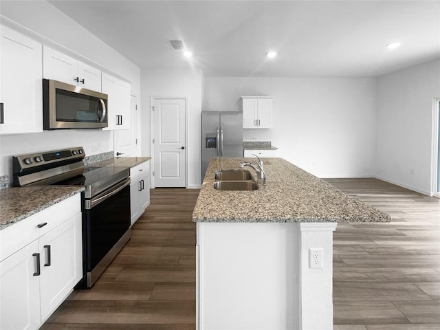 128 Gauntlet Dr, Jarrell, TX 76537 - kitchen with appliances with stainless steel finishes, dark wood-style flooring, a center island with sink, white cabinetry, and recessed lighting