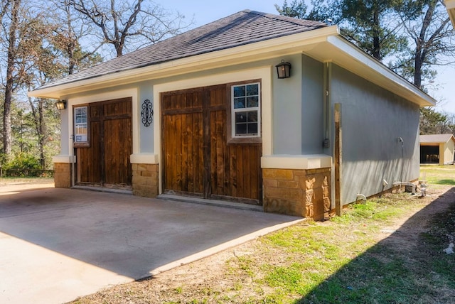 exterior space with a garage and roof with shingles