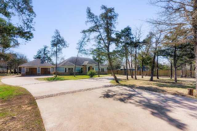 view of front facade featuring driveway, fence, and a front yard