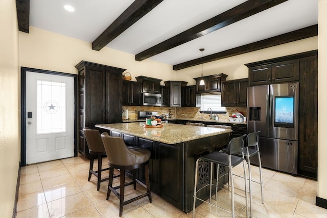 kitchen featuring light stone countertops, appliances with stainless steel finishes, decorative backsplash, and a center island